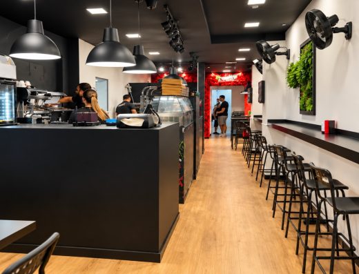 Cafetería reformada por SC Reformas Tenerife, con barra negra, suelo de madera y jardín vertical