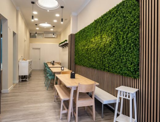 Comedor de un local comercial reformado, con listones de madera y pared vegetal
