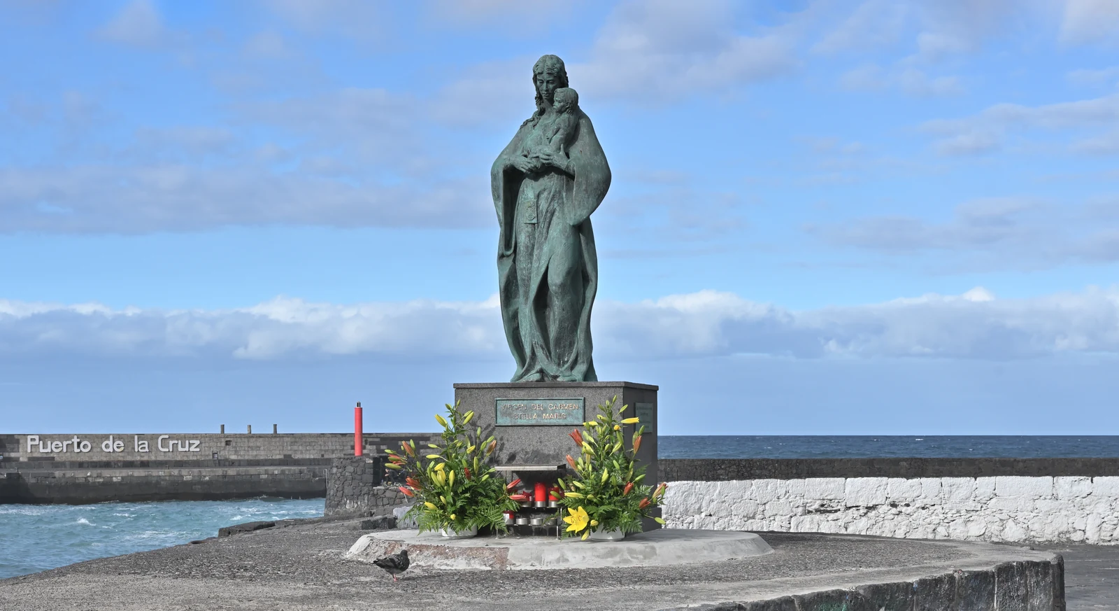 Escultura de la Virgen del Carmen (Stella Maris) en el muelle de Puerto de la Cruz, mirando al mar, con ofrendas florales