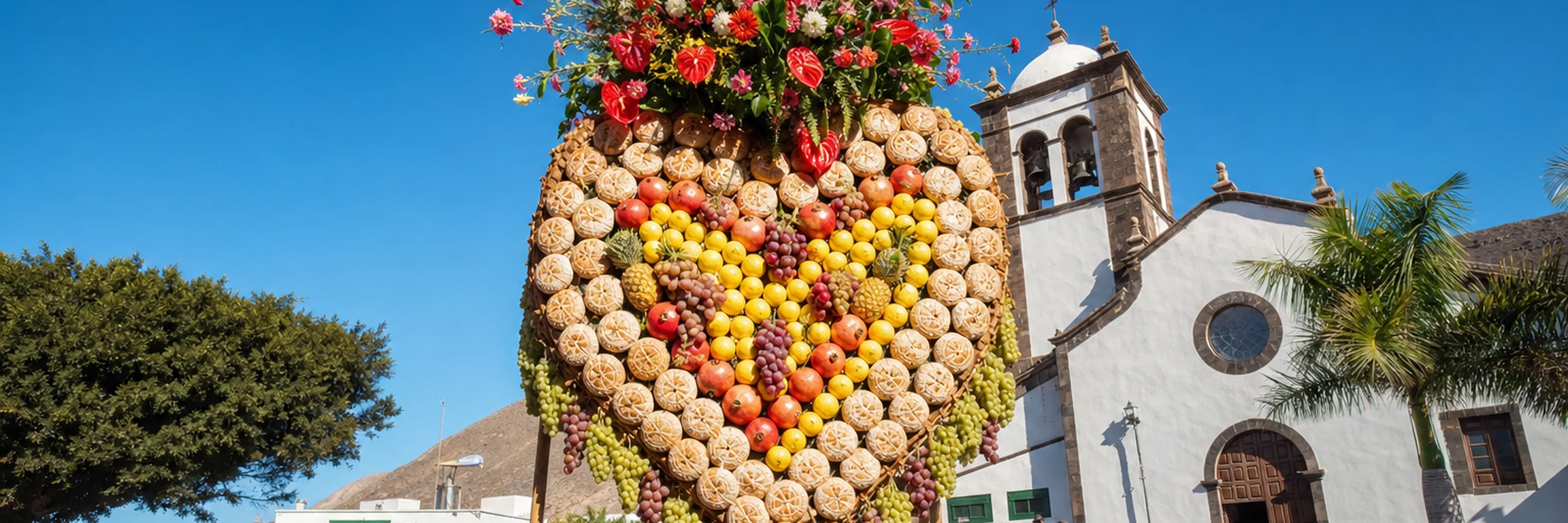 Los Corazones de Tejina: un corazón monumental de frutas, tortas de masa y un ramo de flores se alza a pulso sobre palos de madera en una plaza canaria abarrotada, ante la iglesia, bajo la luz de agosto