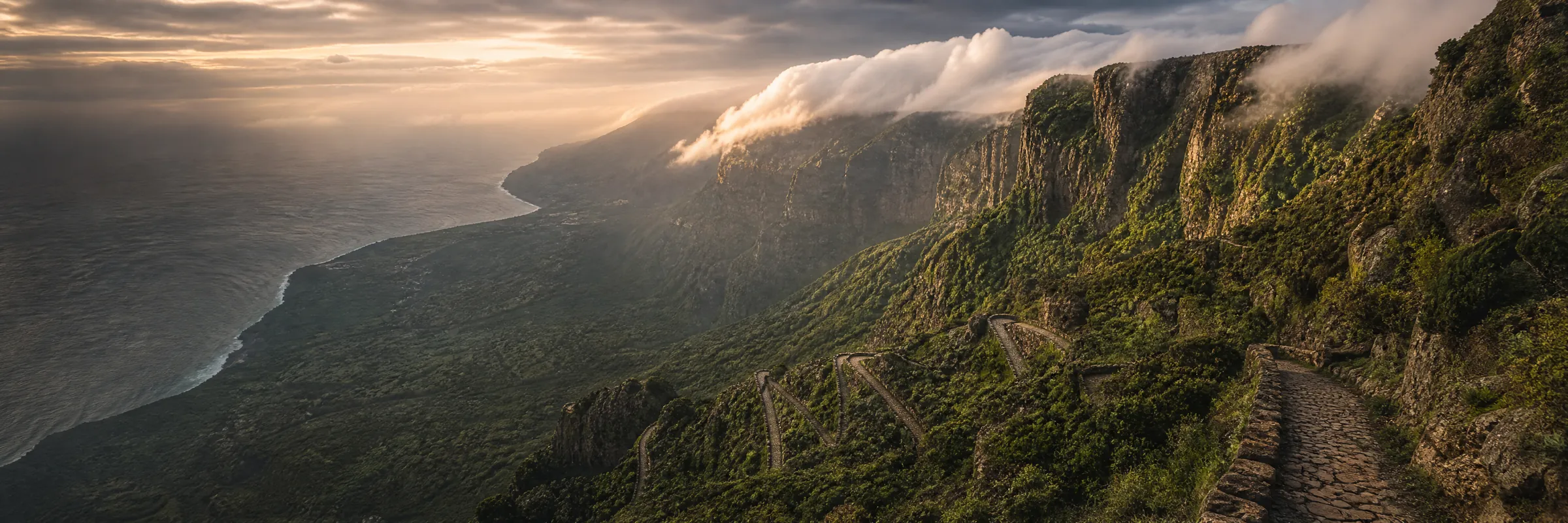 El Camino de Jinama zigzagueando por la cortadura de El Hierro, con el valle de El Golfo y el Atlántico al fondo bajo un mar de nubes
